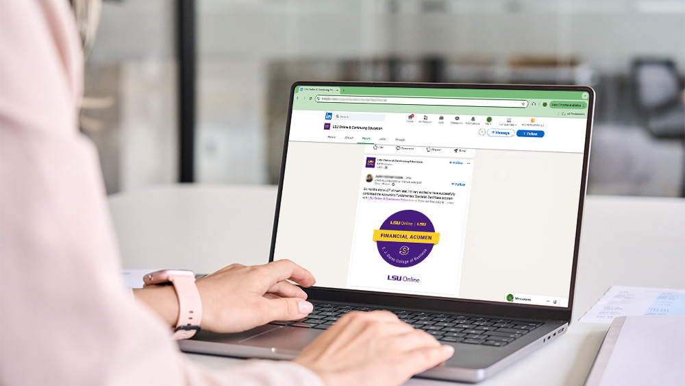 A woman is sitting at a desk, typing on a laptop